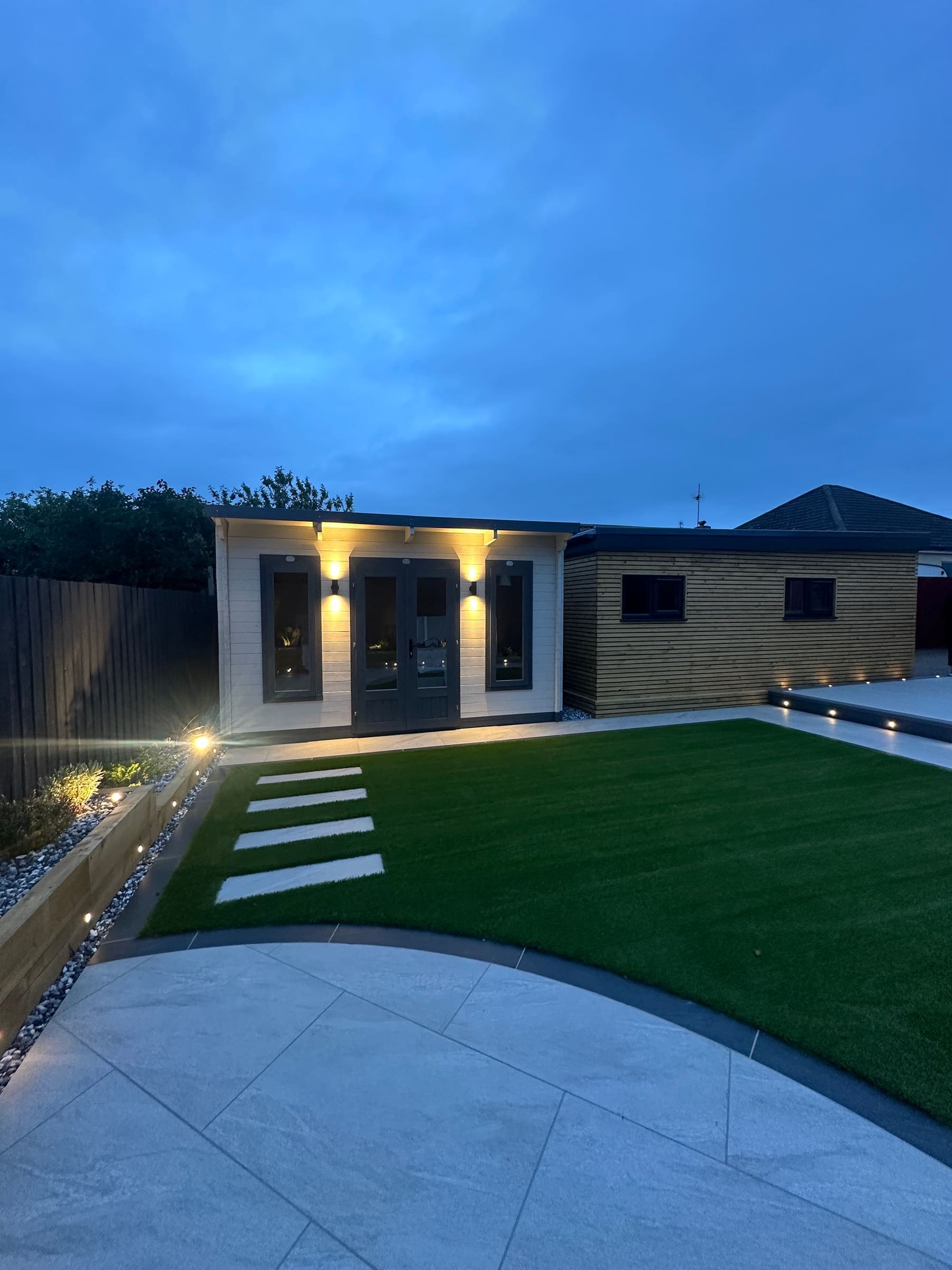 Insulated garden room with exterior lighting and an artificial grass lawn in Liverpool