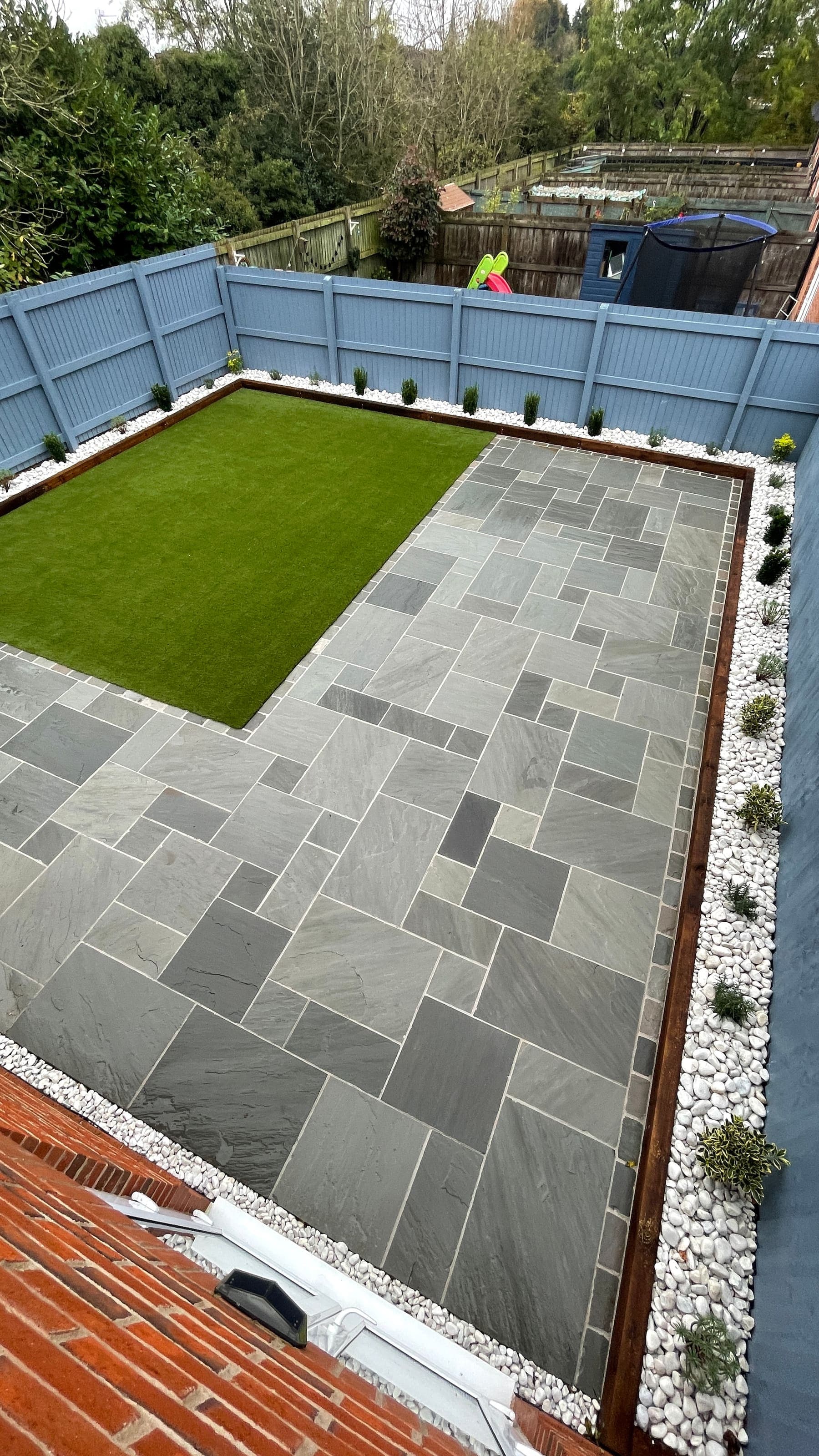 Grey porcelain patio with artificial grass and a fenced boundary in Liverpool