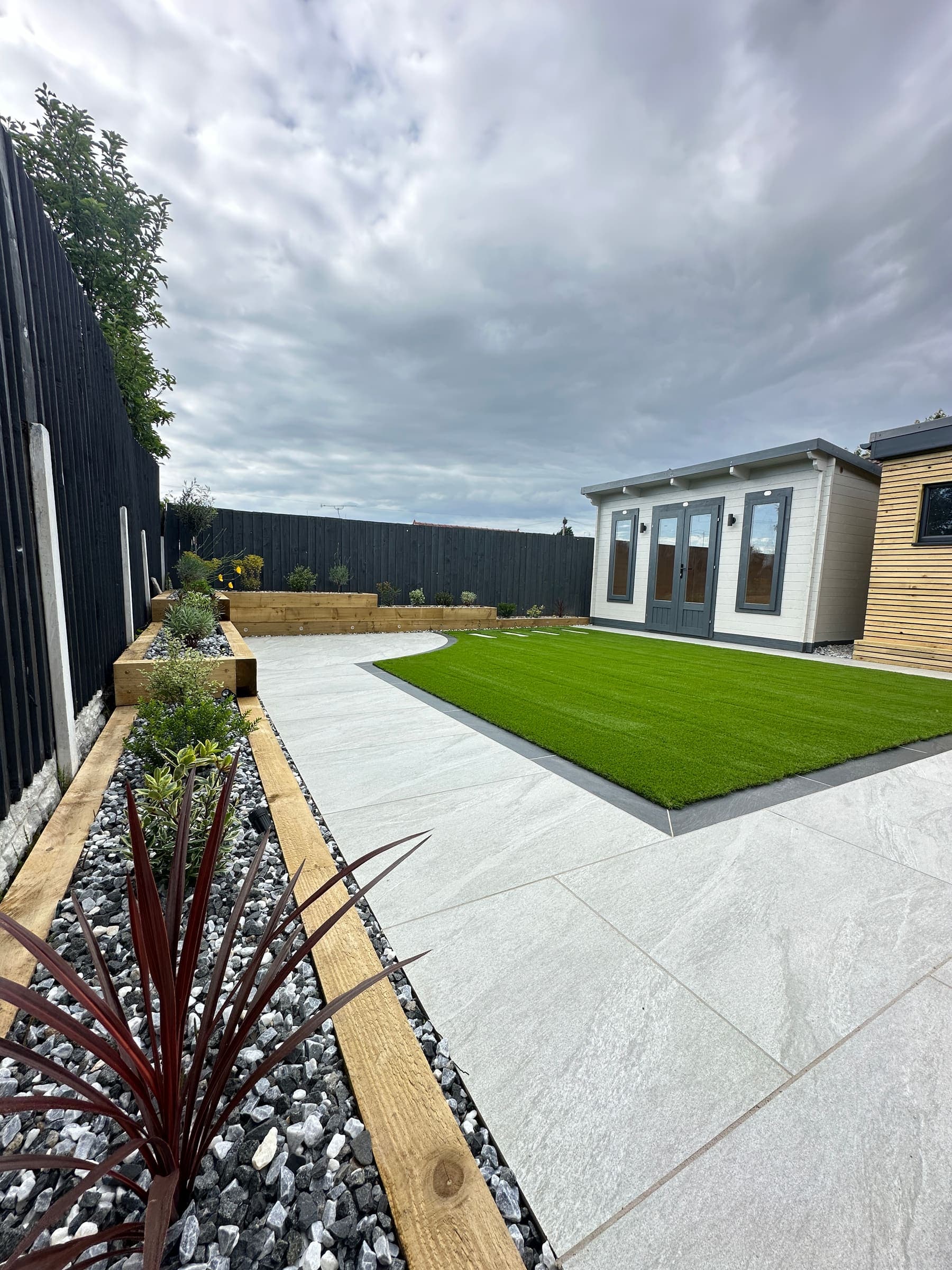 Contemporary summer house with patio paving and artificial grass in a Liverpool garden